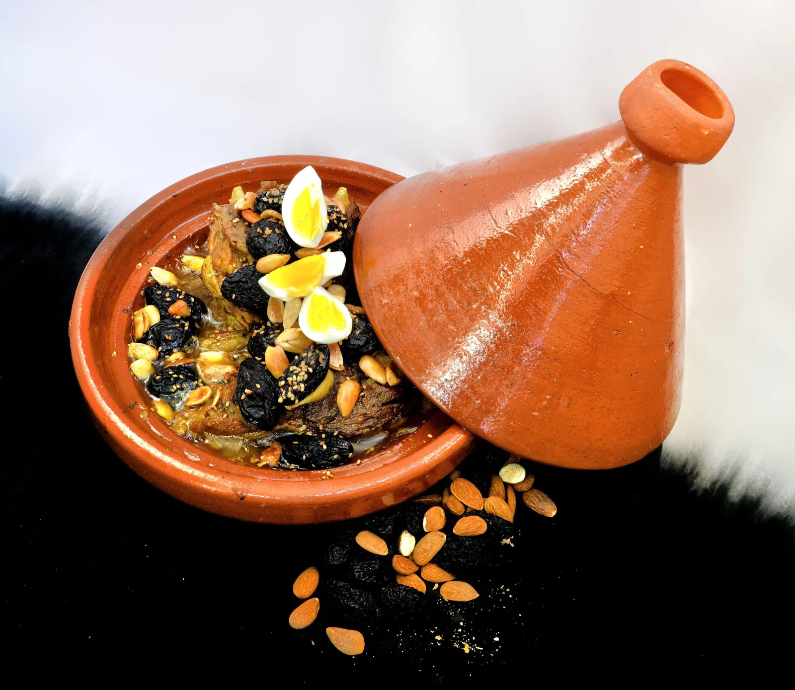 Tajín de ciruelas pasas y almendras, servido en una cazuela de barro