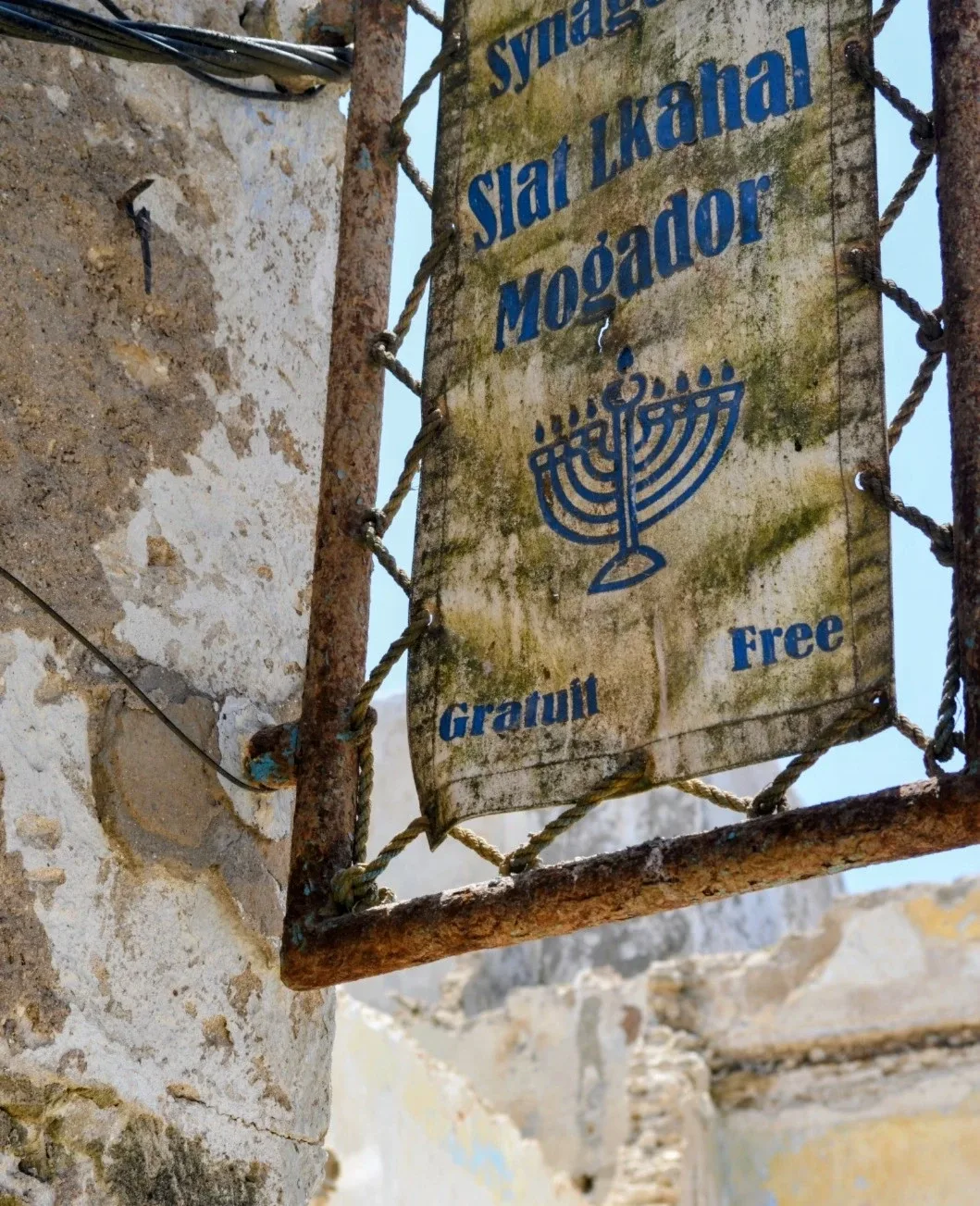 Panneau rouillé de la synagogue Slat Lkahal Mogador, avec une menorah et la mention « Gratuit / Free », dans le Mellah d'Essaouira