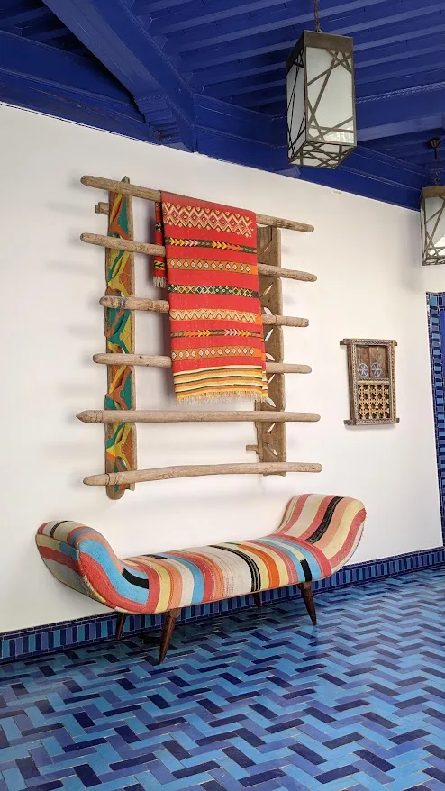 Panca colorata, tappeto appeso e piastrelle blu a spina di pesce nella casa d'ospiti Salut Maroc, medina di Essaouira