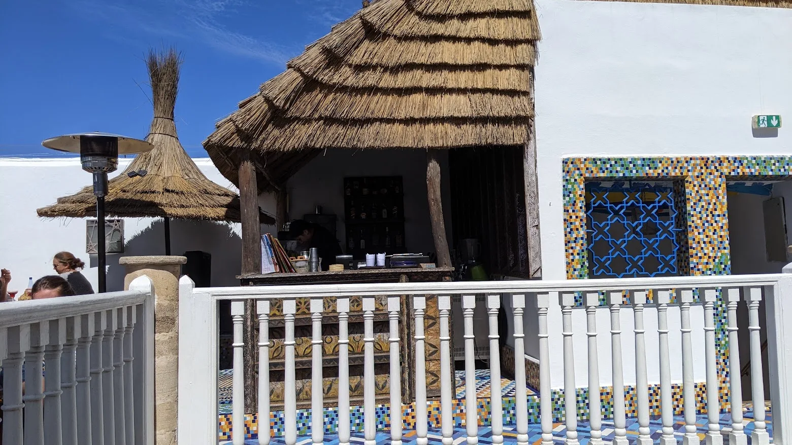 Terrazza di Salut Maroc a Essaouira con il bar sotto un tetto di paglia e mosaici colorati