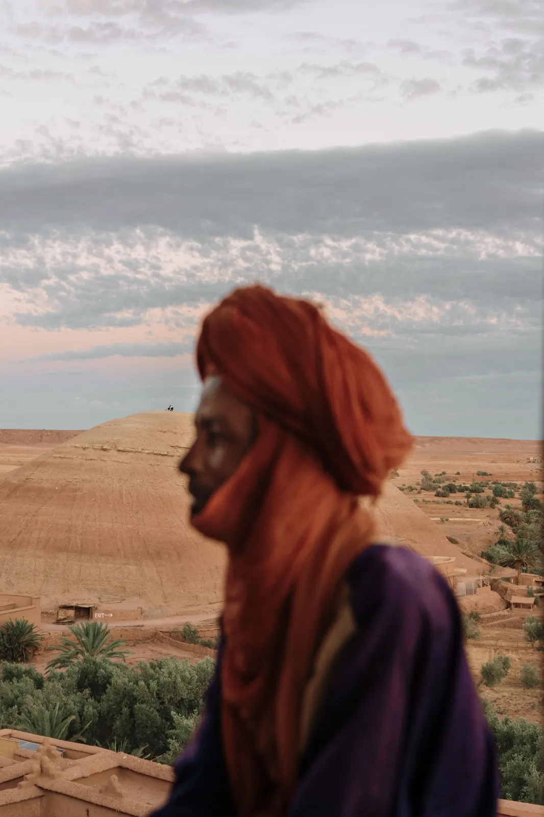 Hombre con turbante tradicional ante los paisajes de tierra y las palmeras del sur marroquí
