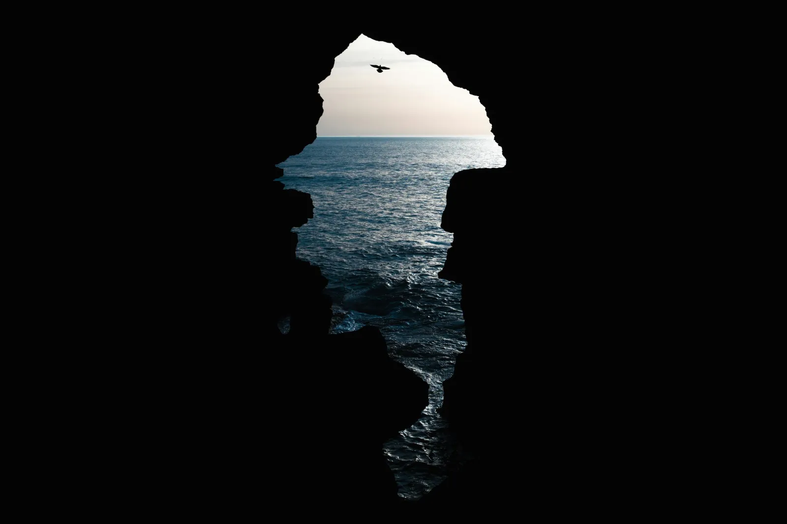 Apertura a forma di sagoma delle Grotte di Ercole sull'oceano, con un uccello in volo