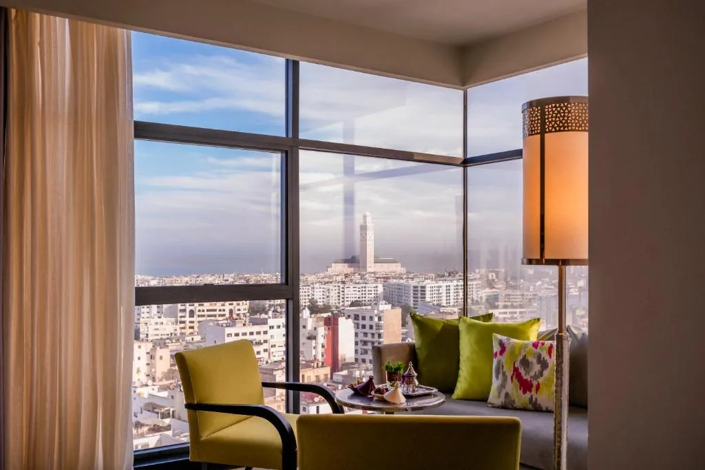 Großes Eckfenster mit einem grünen Sessel und Blick auf die Stadt