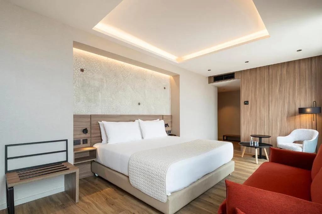 Zimmer mit Doppelbett, hinterleuchtetem Kopfteil mit Sternmotiv, rotem Sofa und Holzvertäfelungen