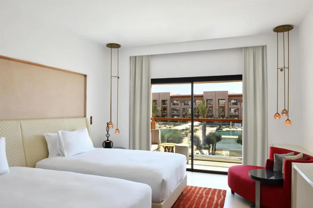 Twin room with a large glass door, a balcony and a red armchair corner