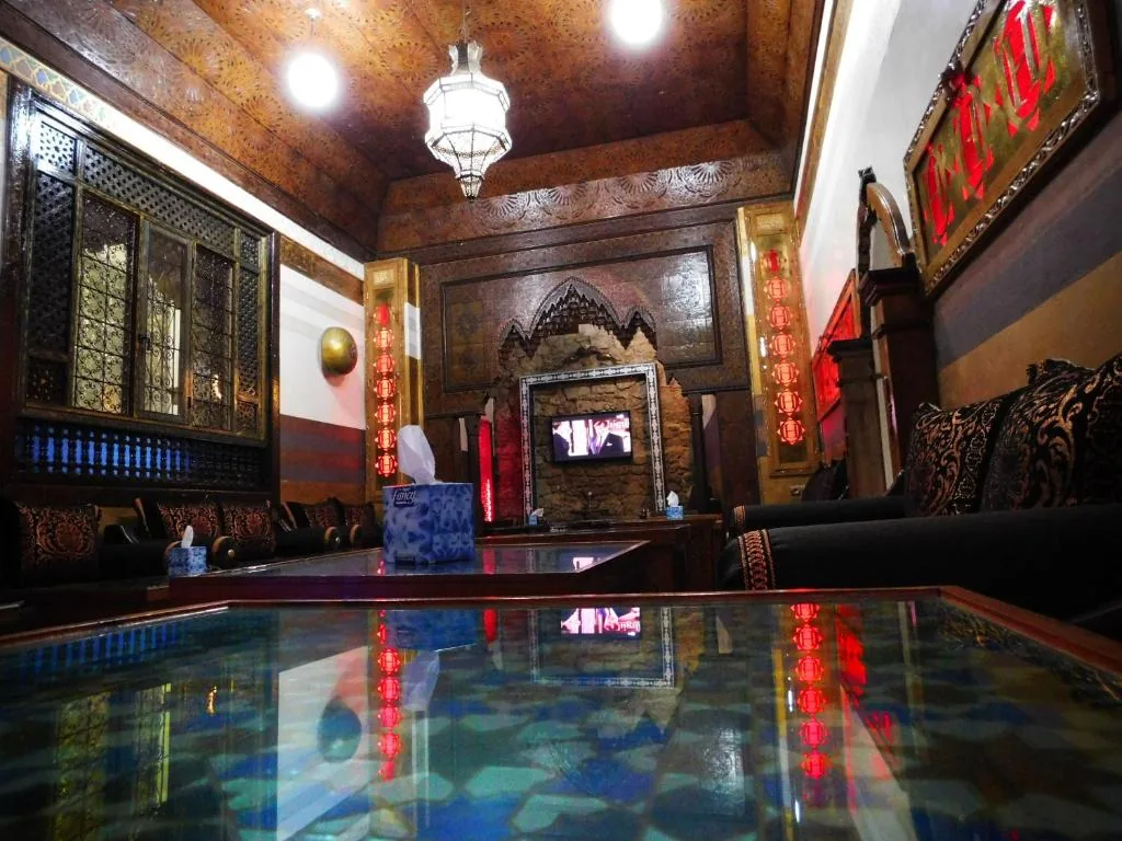 Lounge with carved woodwork, dark banquettes and a large hanging lantern