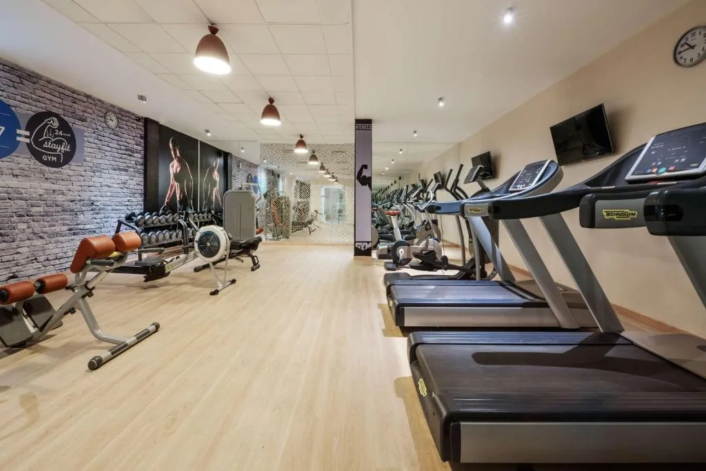 Fitness room with treadmills in a row, weight benches and dumbbells