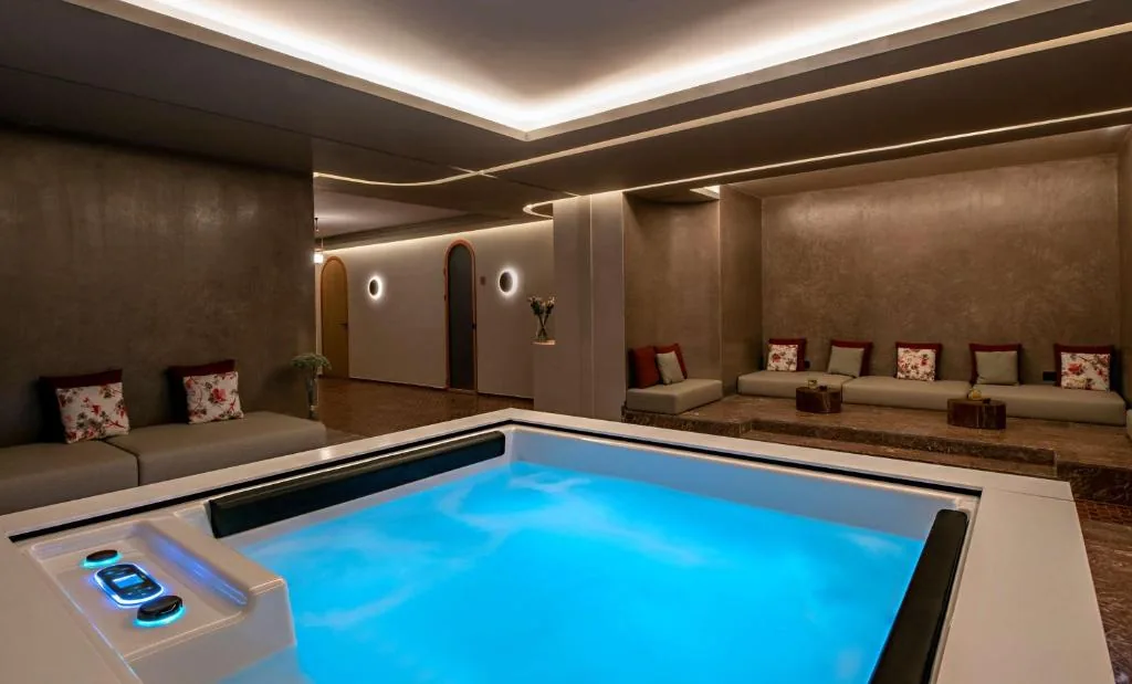Relaxation area with a lit hot tub, among dark walls and low banquettes