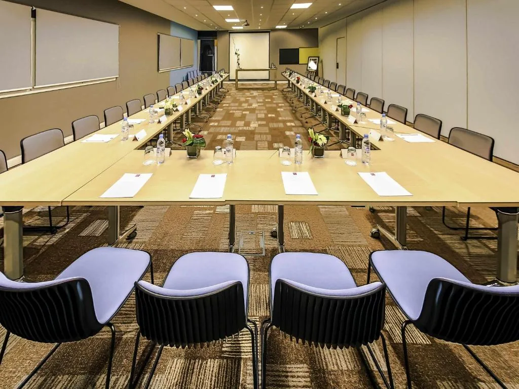 Meeting room with long U-shaped tables and blue-grey chairs