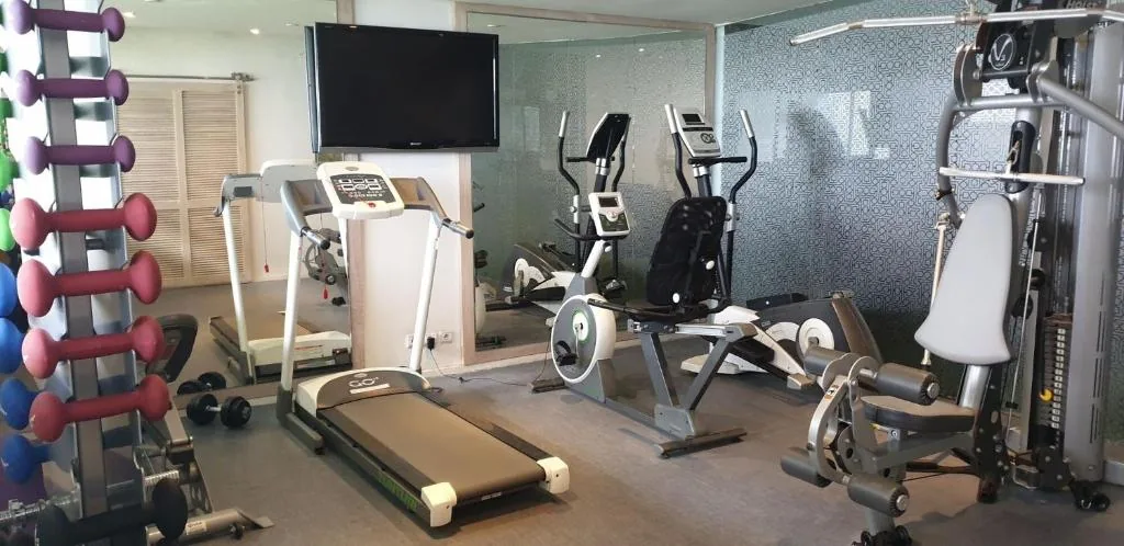 Fitnessraum mit einem Laufband, Fahrrädern, einem Kraftgerät und Hanteln