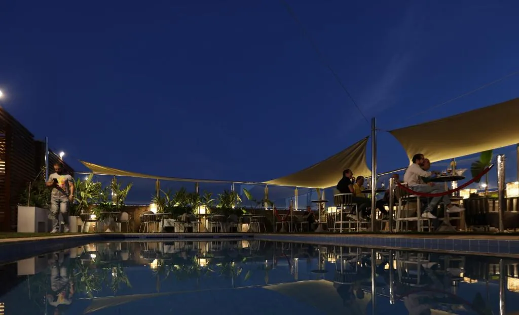 Piscina al bordo di una terrazza, di sera, con vele ombreggianti tese sopra