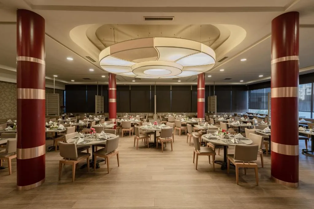 Grande sala con tavoli apparecchiati, due colonne rosse e un soffitto circolare