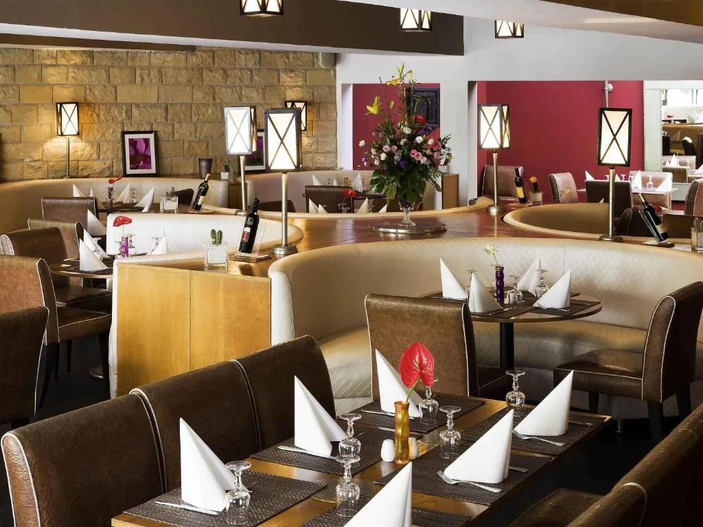 Sala ristorante con banchette beige, tavoli apparecchiati e tovaglioli piegati