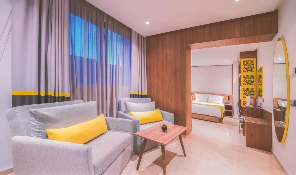 Lounge with grey sofas and yellow cushions, open onto a bedroom