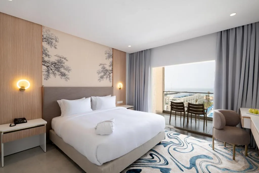 Room with a large bed, a patterned wall, bedside tables and a bathroom visible in the background