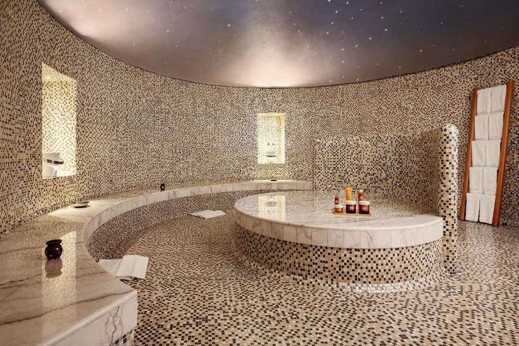 Runder Hammam mit Mosaikverkleidung und einem großen Marmortisch in der Mitte