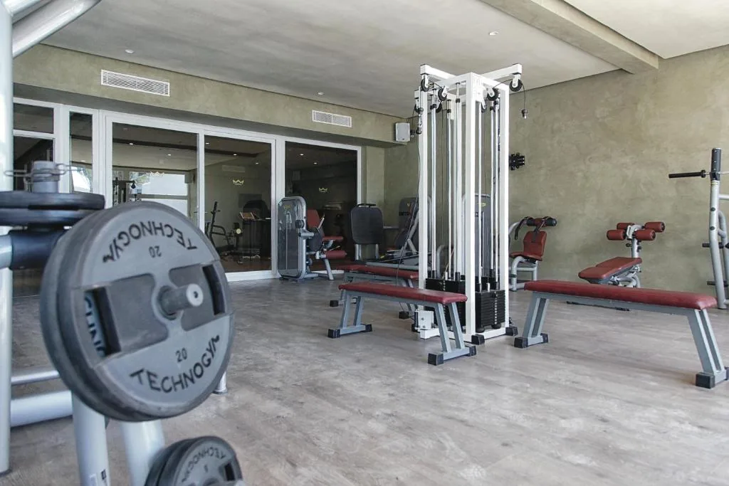 Gym with weight machines and weights in the foreground, on a light wooden floor
