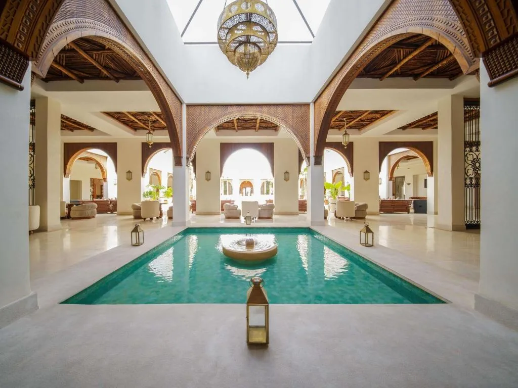 Patio interior con arcos de madera, un estanque turquesa y un farol colocado al borde