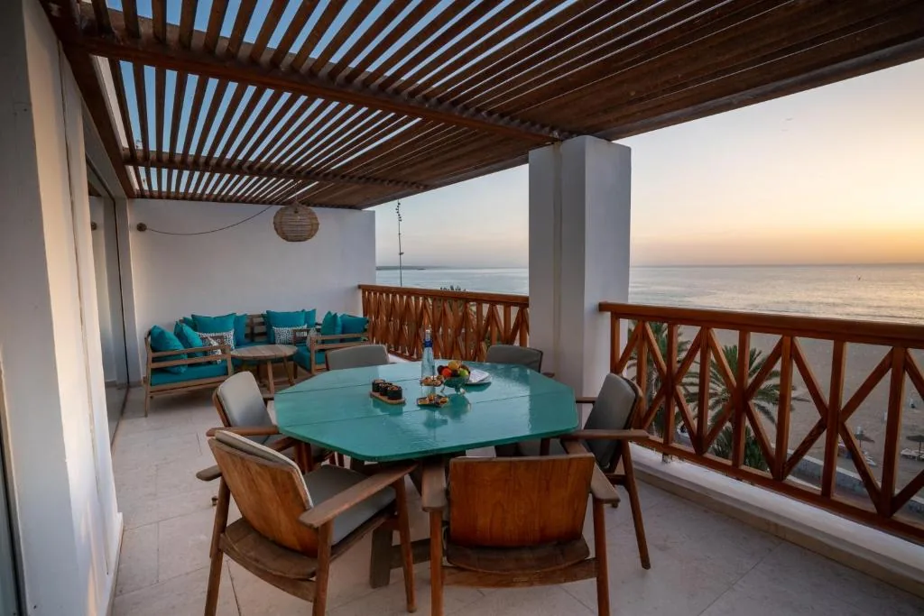 Suite terrace at sunset, with a turquoise octagonal table and corner lounge overlooking the beach and ocean