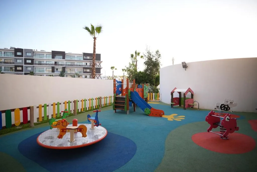 Children's play area with a carousel, a slide and small colourful houses, on a blue and green surface