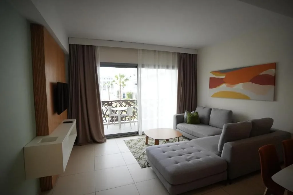 Lounge with a grey corner sofa, a wall-mounted television and a French window opening onto a balcony