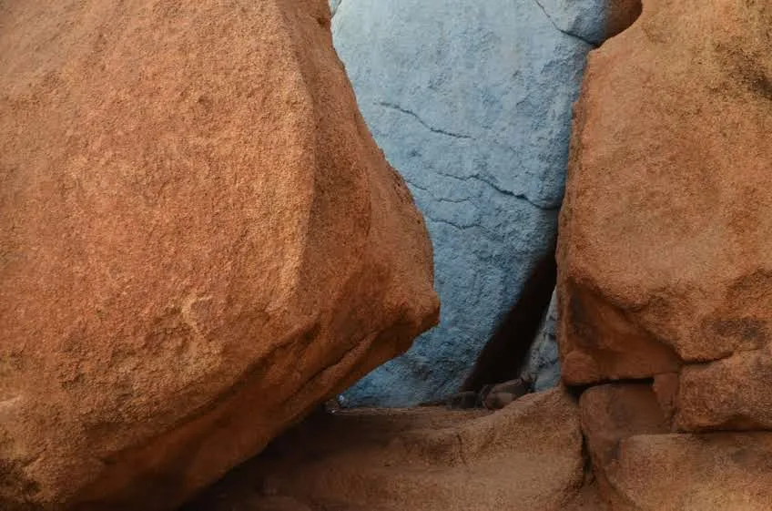 Roche peinte en bleu entre deux blocs de granit orange