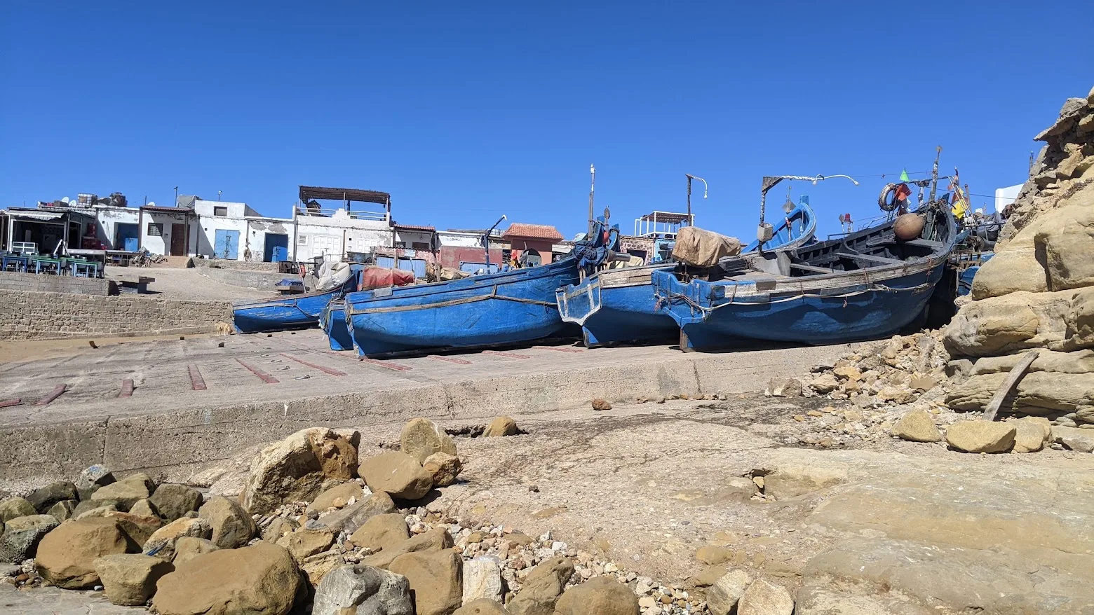Blue fishing boats lined up on a launching ramp beside the ocean