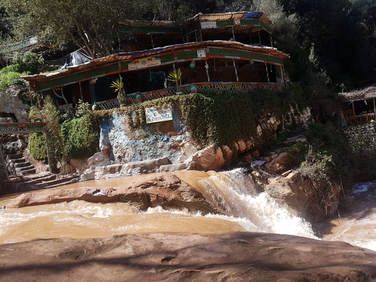 Restaurant traditionnel au bord des Cascades d’Ouzoud avec rivière, nature et paysage du Moyen Atlas au Maroc